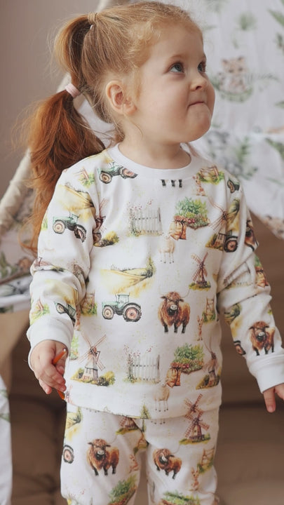 Detailed cotton pyjamas with Highland cows, tractors and green pastures – perfect farm sleepwear for kids.